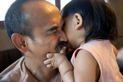 Portrait of Happy father and his son in bedroom. Boy embracing and kiss his Dad.