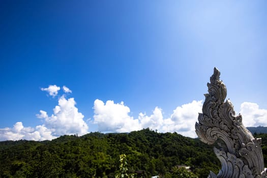 White Naga, Serpent statue on roof of Buddhist temple with blue sky background.