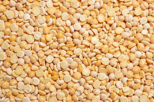 Uncooked Polished Split Peas Background. A Culinary Canvas of Dry Yellow Peas, Creating a Lively and Textured Background for Gourmet Cooking. Scattered Raw Polished Peas. Healthy Eating Ingredients