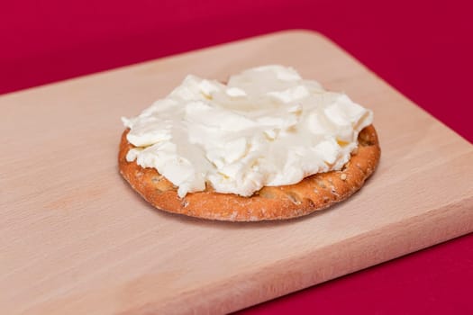 Crispy Cracker Sandwich with Cream Cheese on Wooden Cooking Board on Magenta Background