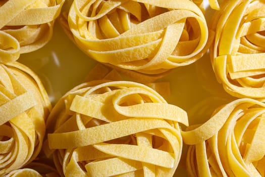 Uncooked Egg-Based Fettuccine Pasta: A Culinary Canvas of Ribbon-Shaped Macaroni, Creating a Lively and Textured Background for Gourmet Cooking. Dry Pasta. Raw Macaroni - Top View, Flat Lay