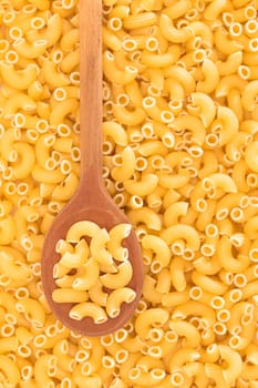 Uncooked Chifferi Rigati Pasta Background with Wooden Spoon. Fat and Unhealthy Food. Classic Dry Macaroni. Italian Culture and Cuisine. Raw Pasta
