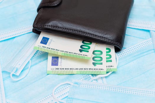 Black Men's Wallet with Euro Money Inside on the Blue Disposable Medical Face Masks. Trade in Medical Masks. Business During a Pandemic or Epidemic