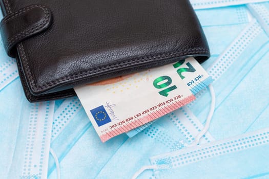 Black Men's Wallet with Euro Money Inside on the Blue Disposable Medical Face Masks. Trade in Medical Masks. Business During a Pandemic or Epidemic