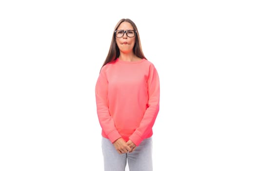 young excited european lady with dark long straight hair in a pink sweater on a white background with copy space.