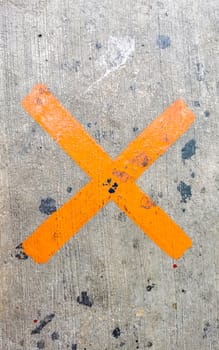 Orange painted cross on the sidewalk in Playa del Carmen Quintana Roo Mexico.