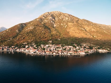 Resort town of Perast at the foot of the mountains in the rays of the setting sun. Montenegro. Drone. High quality photo