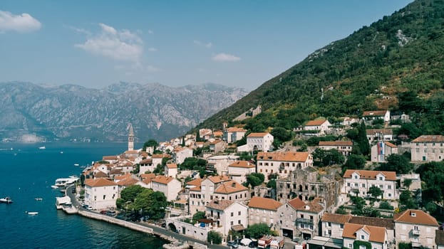 Perast embankment with old houses and a fire station at the foot of the mountains. Montenegro. High quality photo
