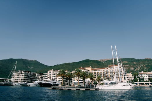 Motor yachts are moored along the pier opposite the Regent Hotel. Porto, Montenegro. High quality photo