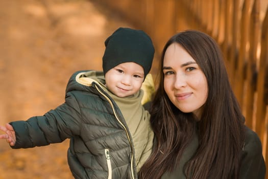 Happy loving young mother hugs her toddler son on the walk.