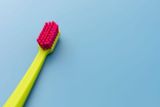 Flat Lay Mockup Green Toothbrush with Pink Bristles Lying On Blue Background, Copy Space For Tex. Morning hygiene, Bathroom accessories. Dental Health Care Template. Horizontal Top View Plane.