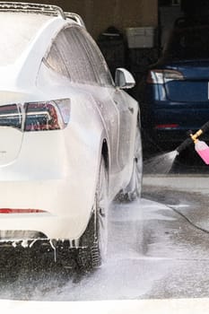 Efficiently cleaning an electric car in the comfort of a suburban driveway, combining eco-consciousness with practicality.