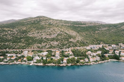 Small resort town on the shores of the Bay of Kotor at the foot of the mountains. Montenegro. Drone. High quality photo