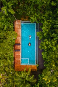 aerial drone view of swimming pool in the jungle of Krabi Thailand, aerial view with a drone above a swimming pool in the rainforest of Thailand. couple of men and women in pool during vacation