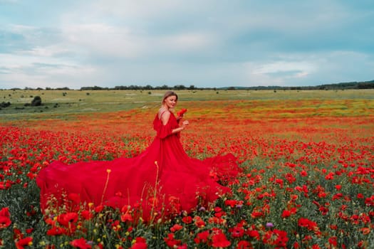 Woman poppy field red dress. Happy woman in a long red dress in a beautiful large poppy field. Blond stands with her back posing on a large field of red poppie