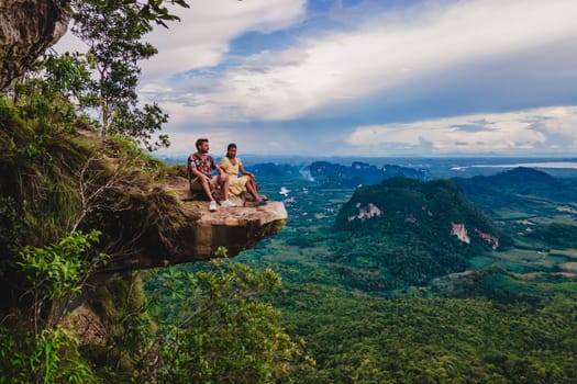 Dragon Crest Mountain Krabi Thailand, a Young traveler sits on a rock that overhangs the abyss, with a beautiful landscape. Dragon Crest or Khuan Sai at Khao Ngon Nak Nature Trail in Krabi, Thailand