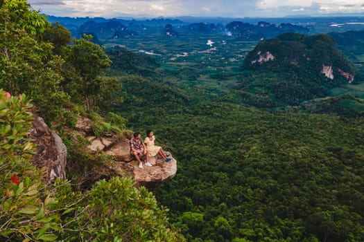 Dragon Crest Mountain Krabi Thailand, a Young traveler sits on a rock that overhangs the abyss, with a beautiful landscape. Dragon Crest or Khuan Sai at Khao Ngon Nak Nature Trail in Krabi, Thailand