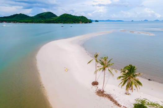 a couple of men and women walking on the beach at the Island Koh Yao Yai Thailand, a beach with white sand and palm trees. Laem Had Beach Ko Yao Yai