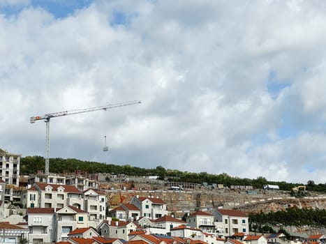Construction crane builds a resort town with colorful buildings on a mountainside. High quality photo