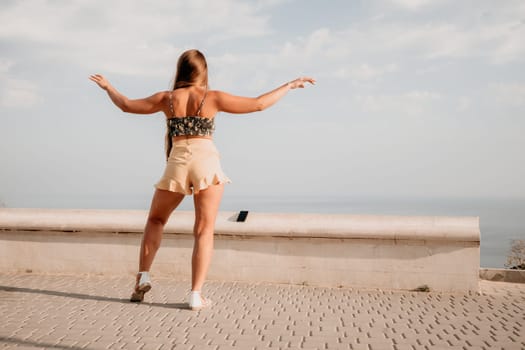 silhouette of a happy woman who dances, spins and raises her hands to the sky. A woman is enjoying a beautiful summer day.