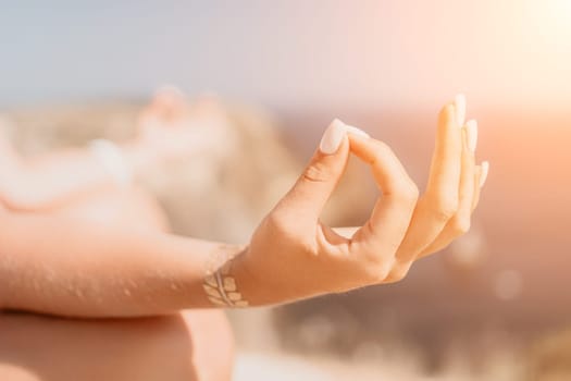 Woman meditating in yoga pose silhouette at the ocean, beach and rock mountains. Motivation and inspirational fit and exercising. Healthy lifestyle outdoors in nature, fitness concept.