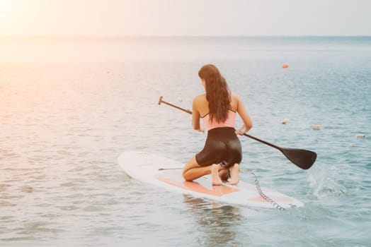 Sea woman sup. Silhouette of happy young woman in pink bikini, surfing on SUP board, confident paddling through water surface. Idyllic sunset. Active lifestyle at sea or river. Slow motion