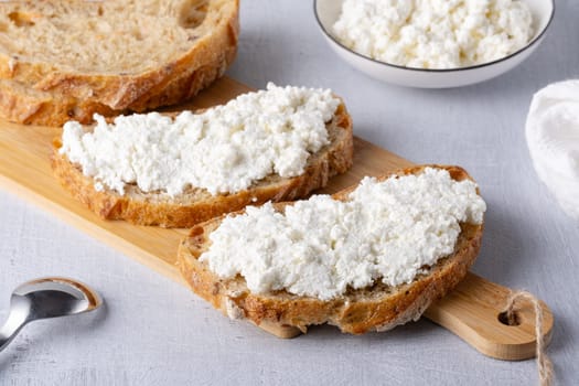 Bread with curd cheese on wooden board.