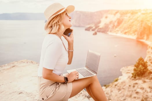 Digital nomad, Business woman working on laptop by the sea. Pretty lady typing on computer by the sea at sunset, makes a business transaction online from a distance. Freelance remote work on vacation