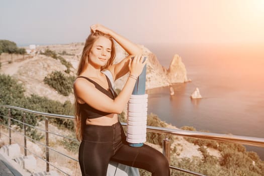 Fitness woman sea. Outdoor workout on yoga mat in park near to ocean beach. Female fitness pilates yoga routine concept. Healthy lifestyle. Happy fit woman exercising with rubber band in park.