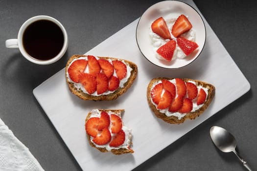 Homemade Crispbread toast with Cottage Cheese and Strawberry on white wooden board.