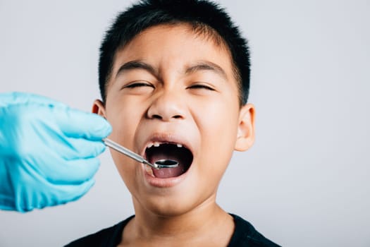 In a pediatric dentist's practice a doctor examines a child's mouth after extraction of a loose milk tooth. Dental instruments assist in examination. Doctor uses mouth mirror to checking teeth cavity