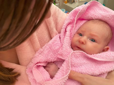 Woman Holding a newborn Baby after bathing in a Pink Towel. Happy family kid dream concept.