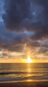 Seascape with beautiful sunset on horizon line and clouds, vertical frame