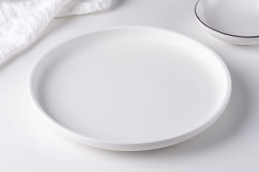 Empty white plate on a white table.