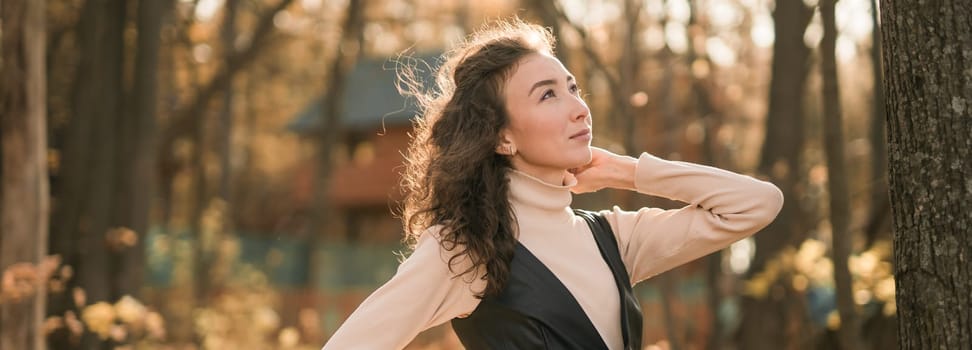 Attractive young woman walking in autumn park, happy mood and fashion style trend and curly long brown hair. Fall season and pretty female portrait. Millennial generation