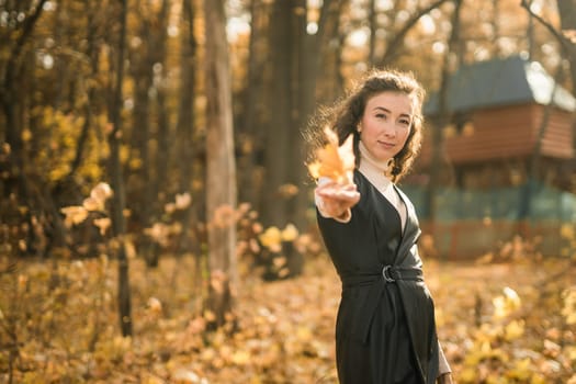 Attractive young woman walking in autumn park, happy mood and fashion style trend and curly long brown hair. Fall season and pretty female portrait. Millennial generation