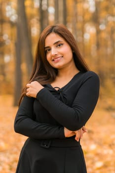 Close up portrait of pretty indian young woman enjoying warm autumn sunny day vacation outdoors. Generation z and gen z concept. Fall Season.