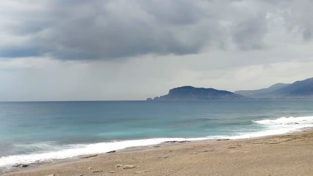 Sea coast, stormy sky over turquoise sea, view from shore.