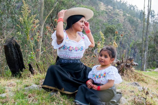 young mother and daughter enjoying a sunny day together in the ecuadorian amazon with their traditional attire and dresses from otavalo, ecuador. women's day. High quality photo