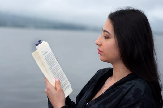 portrait of an attractive woman from ecuador reading a textbook by the sea. book day. High quality photo