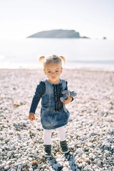 Little girl stands on the seashore with a toy. High quality photo