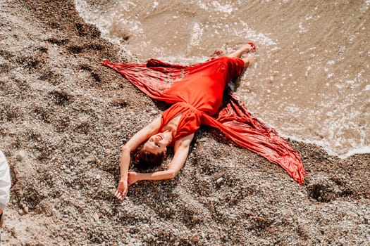 Woman red dress sea. Female dancer in a long red dress posing on a beach with rocks on sunny day.