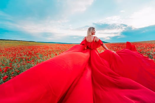 Woman poppy field red dress. Happy woman in a long red dress in a beautiful large poppy field. Blond stands with her back posing on a large field of red poppie