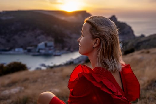 Woman sunset sea mountains. Happy woman siting with her back on the sunset in nature in summer posing with mountains on sunset, silhouette. Woman in the mountains red dress, eco friendly, summer landscape active rest.