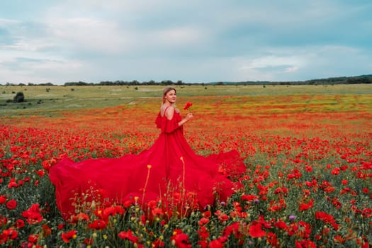 Woman poppy field red dress. Happy woman in a long red dress in a beautiful large poppy field. Blond stands with her back posing on a large field of red poppie