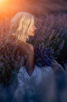 Blonde woman poses in lavender field at sunset. Happy woman in white dress holds lavender bouquet. Aromatherapy concept, lavender oil, photo session in lavender.