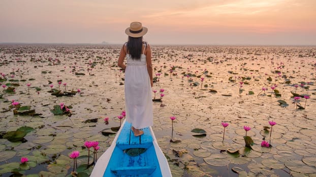 The sea of red lotus, Lake Nong Harn, Udon Thani, Thailand. Asian woman with hat and dress on a boat at the red lotus lake in the Isaan