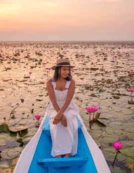 The sea of red lotus, Lake Nong Harn, Udon Thani, Thailand. Asian woman with hat and dress on a boat at the red lotus lake in the Isaan at sunrise