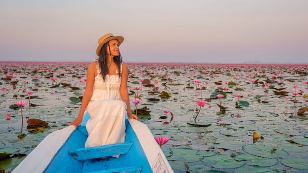 The sea of red lotus, Lake Nong Harn, Udon Thani, Thailand. Asian Thai woman with a hat and dress on a boat at the Red Lotus Lake in the Isaan