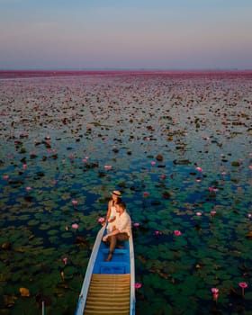 Sunrise at the sea of red lotus, Lake Nong Harn, Udon Thani, Thailand, a couple of men and woman in a boat at sunrise at the Red Lotus Lake in the Isaan